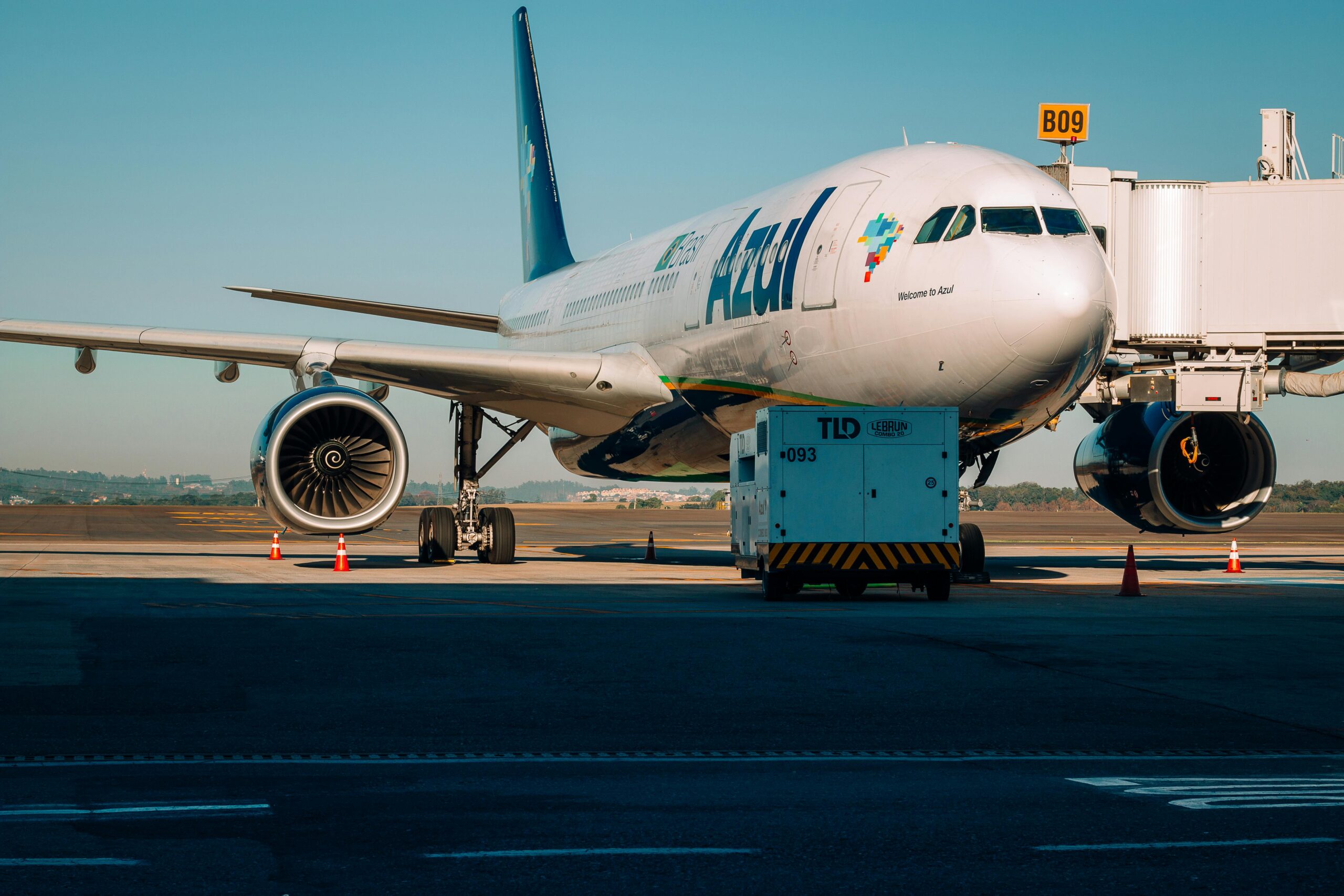A commercial airplane docked at an airport gate, ready for boarding under clear skies.